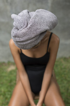 Young woman sitting on a chair with a towel on her head