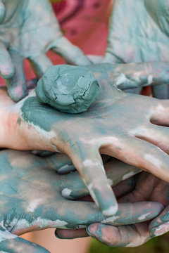 Child models handicraft in lump of clay by hands