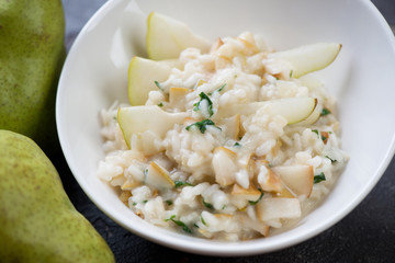 Risotto with pears served in a white bowl, close-up, selective focus