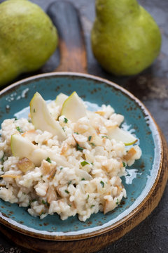 Close-up of risotto with pears, cheese and parsley served on a turquoise plate, selective focus