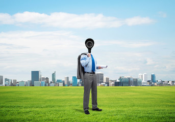 Camera headed man standing on green grass against modern cityscape