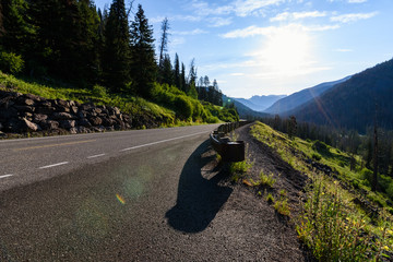 Mountain road view. Morning misty mountains. Sun glare. Yellowstone National Park.