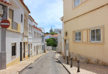 Fototapeta na wymiar Typical european touristic small town street in Lagos Algarve coast, Portugal. Traditional historic old city architecture, residential area, lifestyle theme, summer scene with stop sign and empty road