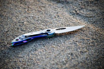 Obraz premium Folding knife on the sand. EDC knife. Pocket instrument