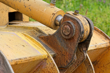 Close up of repaired rusted and yellow excavator bucket joint angle view