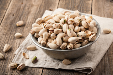 Pistachio nuts in a vintage bowl on wooden table