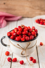 wild strawberry in a white Cup on wooden background