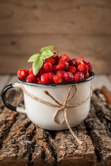 wild strawberry in a white Cup on wooden background.