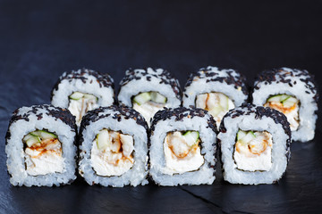Tasty fresh maki sushi rolls with smoked eel and cream cheese in black sesame, delicious seafood