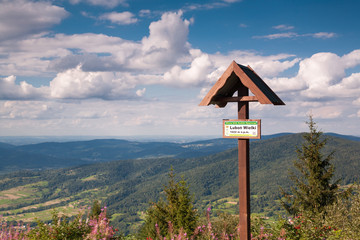 Info plate on the peak Lubon Wielki.View from the top of Lubon Wielki in Beskid Mountains. One of the lower peaks popular tourist destination with mountain chalet on top.