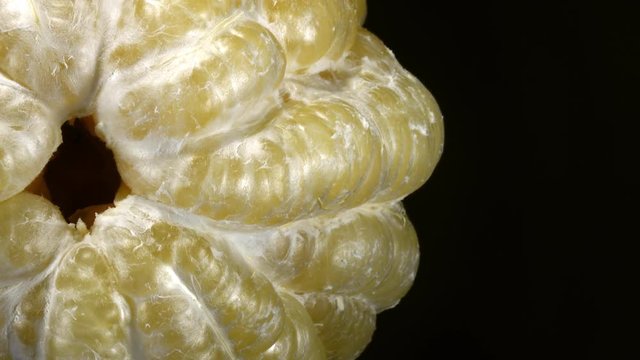 Excellent top view of closely peeled huge pomelo, rotating clockwise on black background with side center. Vibrant flat lay of yummy fresh fruit with amazing texture close up in 4k, 3840x2160, clip.