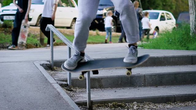 Image of legs of skateboarder in casual sport outfit jumping up and grinding on railing outdoors. Teenager is doing nosegrind trick sliding on handrail. Man on board demonstrating healthy lifestyle.