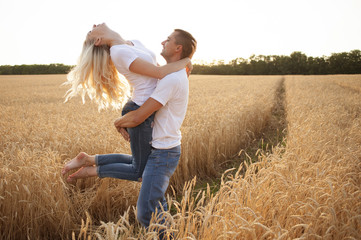 A man and a woman are playing in a wheat field. Happy together