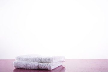 Fototapeta na wymiar Spa. Two white towels on a pink marble table. White background.