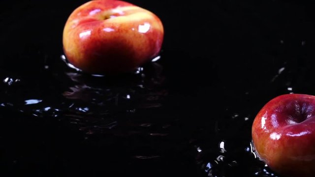 Amazing flat peaches, falling on black surface with shallow water on dark background in back-light. Excellent slow motion for vibrant intro in full HD. Shooting with high-speed, 240fps, camera.