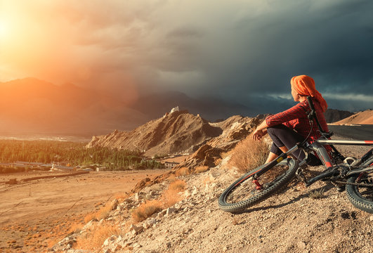 Woman bicycle traveler looking to Ladakh mountain range, India