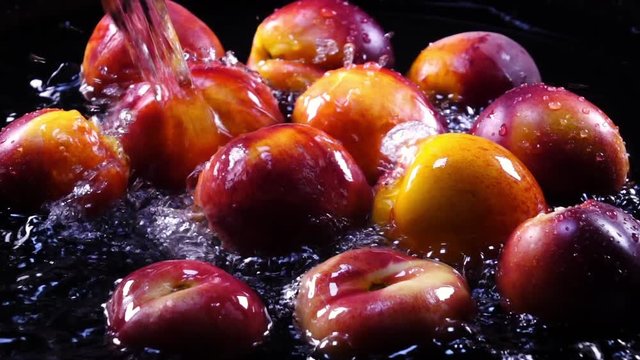 Amazing bathing for fresh nectarines and flat peaches, laying in shallow water on black background in back-light. Excellent slow motion for vibrant intro in full HD. Shooting with high-speed camera.