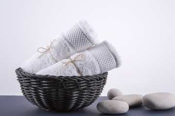 Two white towels in a black basket. The background is white.