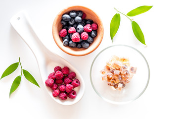 Making summer preserve. Raspberry, blueberry and sugar on white background top view
