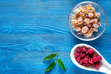 Preparing raspberry jam. Berries and sugar on blue wooden background top view copyspace