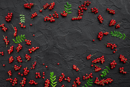 Berry frame. Red currant and leaves on black table background top view copyspace