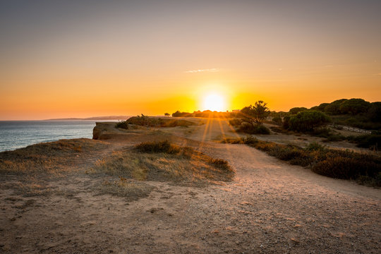 Beautiful colorful sunset in Algarve Portugal. Peaceful  water and cliffs.