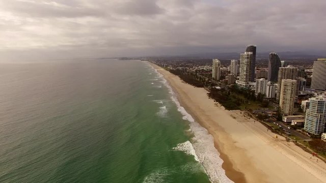 Bird eyes view of Goald coast Australia on a cloudy day camera above ocean flying toward skyscrapers