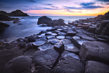 sunset over basalt rocks formation Giant's Causeway, Port Ganny Bay and Great Stookan, County...