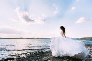 Fototapeta na wymiar Fantastic bride in magnificent wedding dress standing on the sho