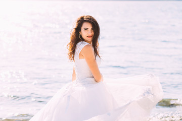 Fototapeta na wymiar bride in charming white dress spinning around at lake