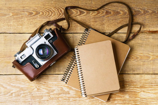 Old retro camera,  spiral blank kraft paper notepad on vintage rustic wooden planks boards. Education photography courses back to  school concept abstract background. Close up, top view, copy space.