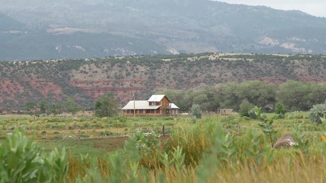 A wooden home sits in a valley overlooked by a desert cliff in rural Torrey, UT.