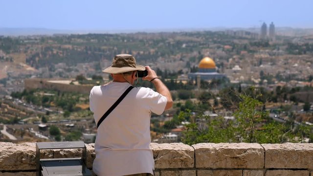 Tourist takes a photo of Jerusalem Old City view. Mount Scopus is a famous Holy Land place and it has a fantastic view to the Old Jerusalem. Jerusalem is a beautiful and popular touristic city.