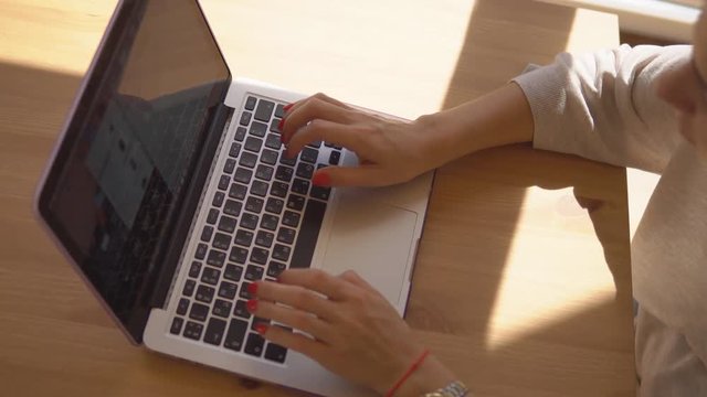 Woman uses laptop on table at the sunny morning