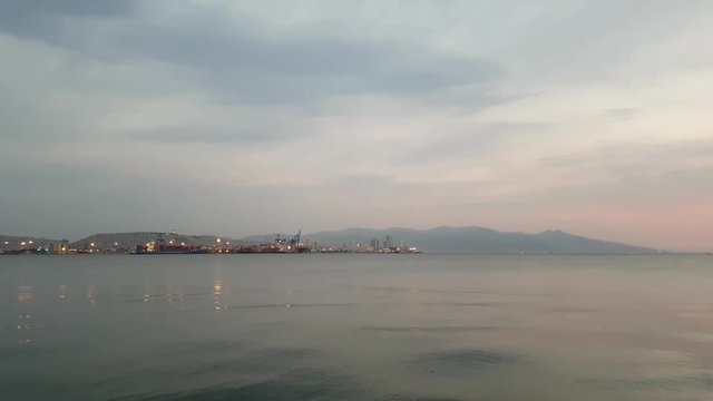 Panoramic view of Izmir city at sunset with gray and orange clouds.
