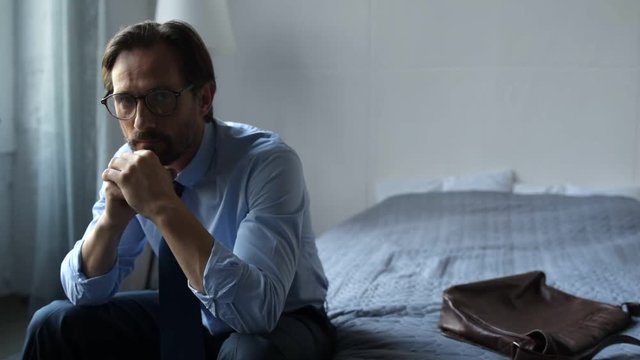 Cheerless depressed businessman sitting at home