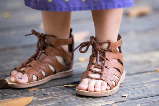 Baby, kid, girl feet in brown, leather sandals