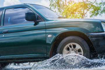 Car runs through flood with water splash during hard rain fall.