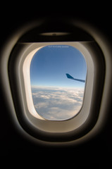 Airplane wing and blue sky through the plane's window