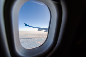 Naklejka premium Airplane wing and blue sky through the plane's window
