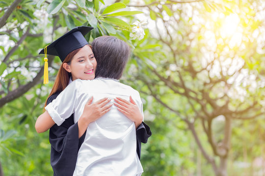 Asian female student and family hug celebrating graduation