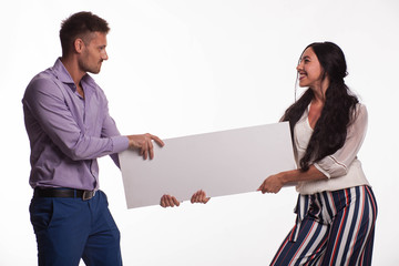 Young jocular woman portrait of a confident businesswoman showing presentation, pointing placard gray background. Ideal for banners, registration forms, presentation, landings, presenting concept.