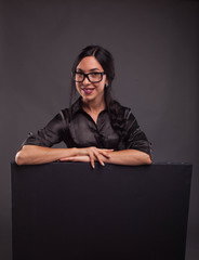 Young happy woman portrait of a confident businesswoman showing presentation, pointing placard black background. Ideal for banners, registration forms, presentation, landings, presenting concept.