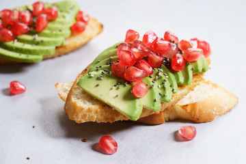 sliced avocado on toast bread with pomegranate seeds.