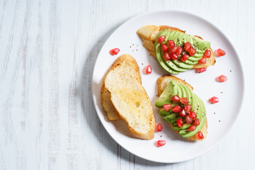 sliced avocado on toast bread with pomegranate seeds.