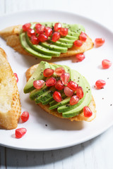 sliced avocado on toast bread with pomegranate seeds.