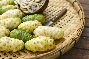  Noni slices in the bamboo basket with old knife on old wooden table