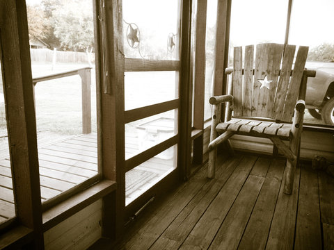 Black & White image of an empty chair on a screened-in porch, with backlighting creating a glowing halo effect, like a memory.