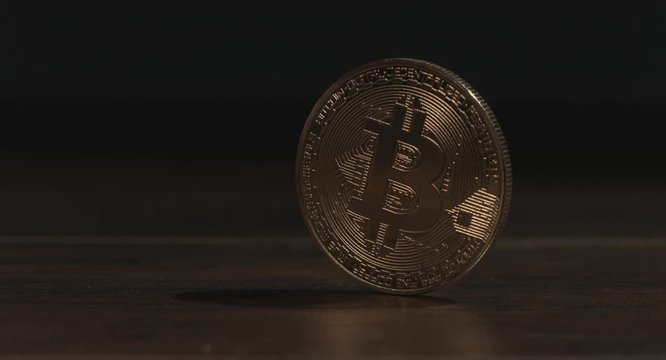Gold bitcoin coin on table.