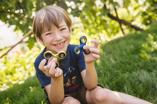 Boy playing with two fidget spinner stress relieving toys outdoor